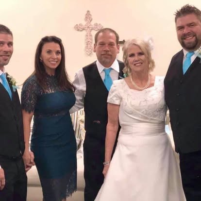 Sharp and grinning, standing with family at the wedding.